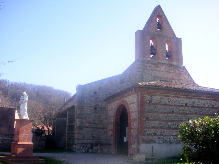 Une &eacute;glise avec une statue devant elle, soulignant l'architecture et l'art religieux de l'endroit.