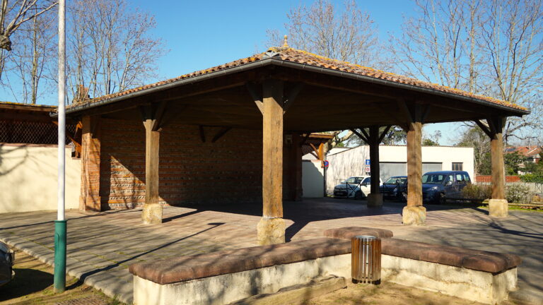 Pavillon en bois abrit&eacute; avec des v&eacute;hicules stationn&eacute; sous sa structure.